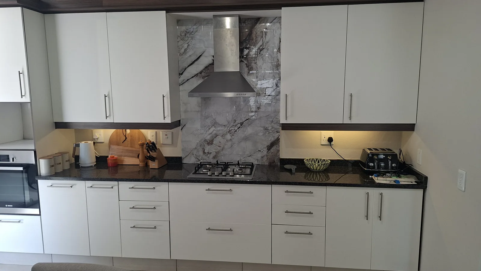 Wrapped kitchen cupboards and stone-look splashback in a Durban kitchen, refinished rather than replaced